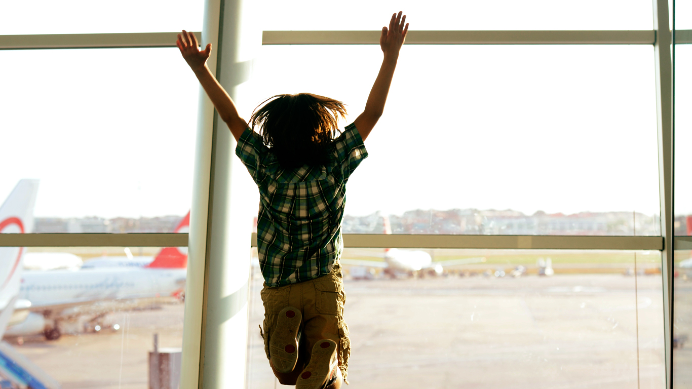 criança pulando de felicidade perto de janela em aeroporto